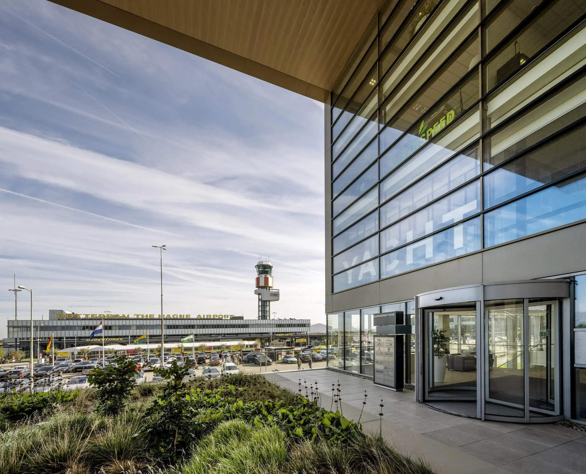 Vooraanzicht van Rotterdam The Hague Airport met de verkeerstoren en een modern kantoorgebouw op de voorgrond.